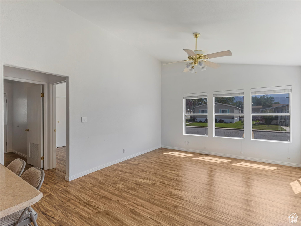 Unfurnished living room with high vaulted ceiling, light wood-style floors, ceiling fan, and baseboards