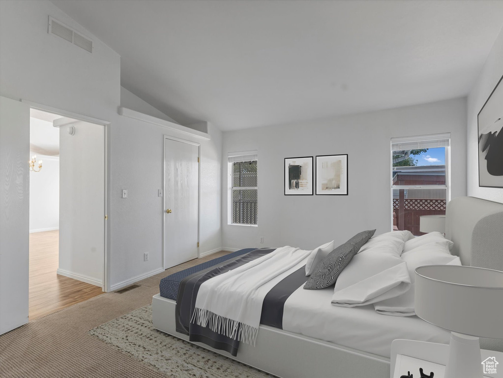 Carpeted bedroom featuring a chandelier and lofted ceiling