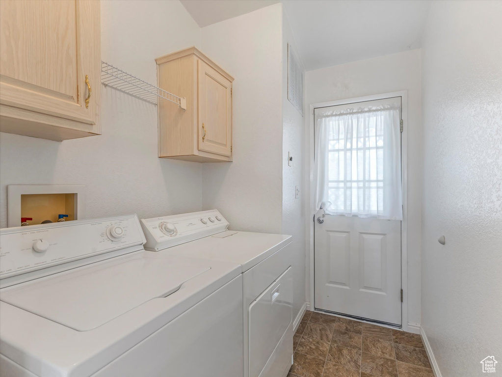 Laundry area featuring washing machine and clothes dryer, baseboards, cabinet space, and stone finish flooring