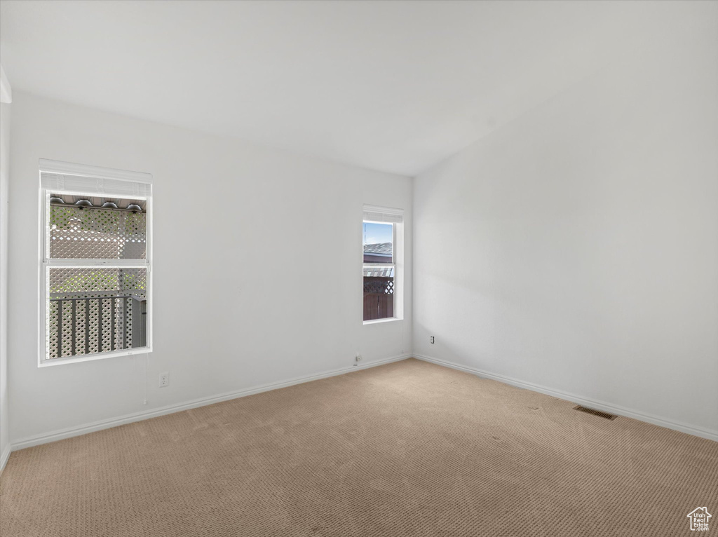 Spare room featuring light colored carpet and baseboards