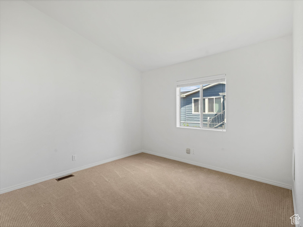 Empty room with light colored carpet and baseboards