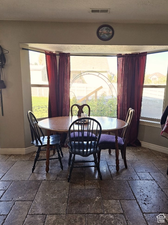 Dining space featuring stone tile floors and baseboards