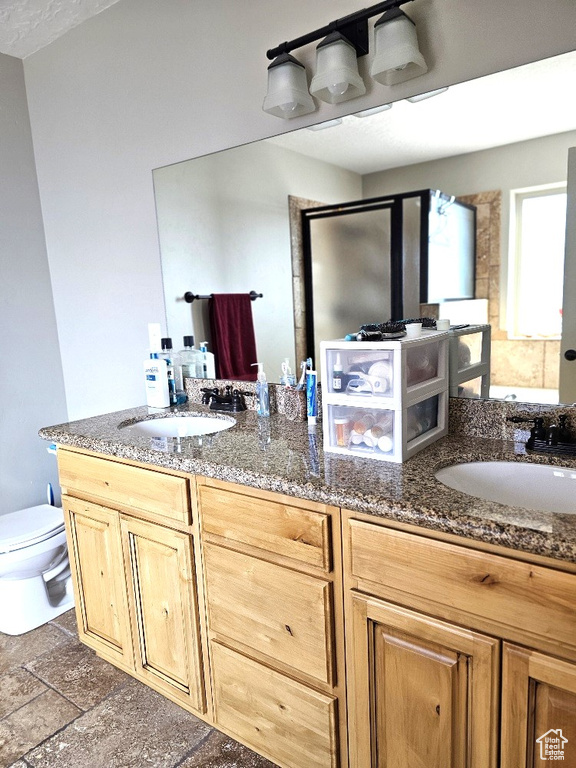 Bathroom featuring double vanity, toilet, and stone tile flooring