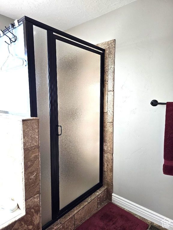 Bathroom featuring a stall shower and a textured ceiling