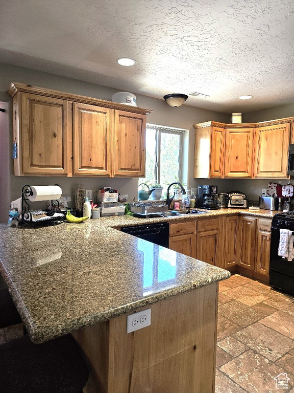 Kitchen with black appliances, a peninsula, recessed lighting, a kitchen breakfast bar, and light stone countertops