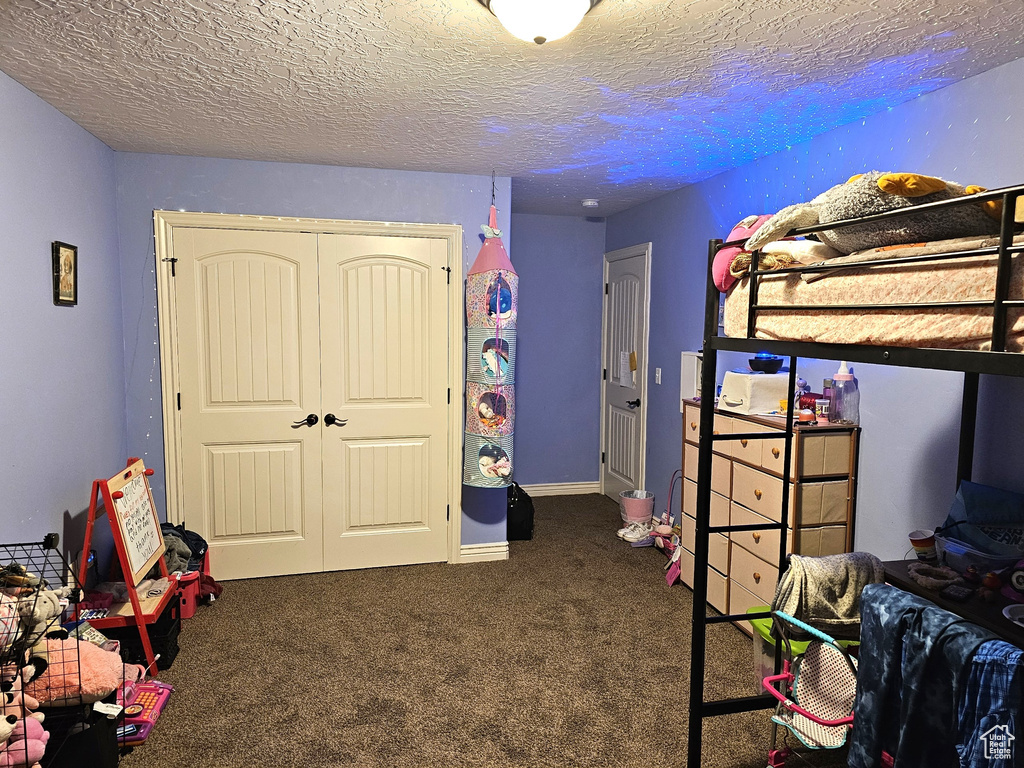 Carpeted bedroom featuring a closet and a textured ceiling