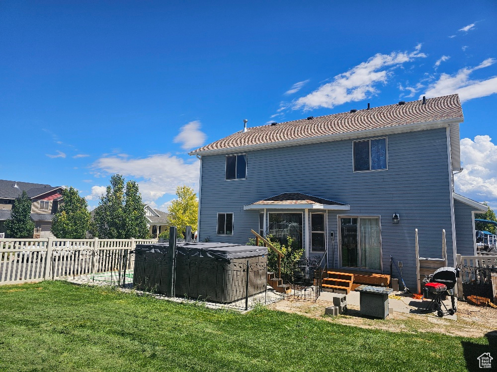 Rear view of property featuring a hot tub and a patio