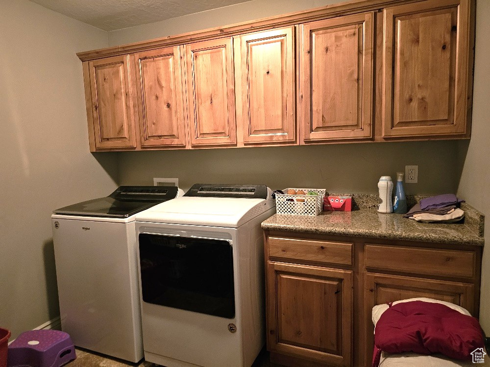 Washroom featuring cabinet space and washing machine and dryer