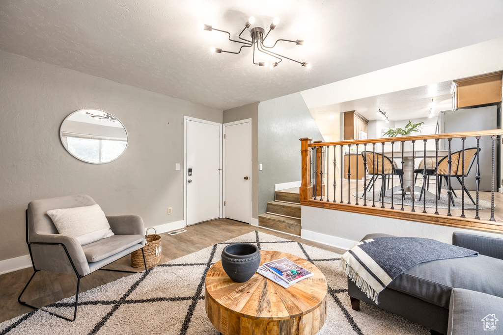 Living room featuring wood finished floors, baseboards, stairs, and a chandelier