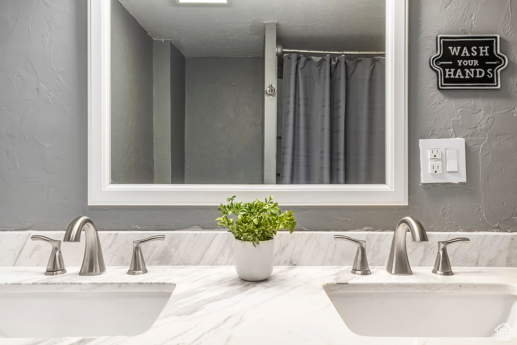 Bathroom featuring double vanity and a textured wall