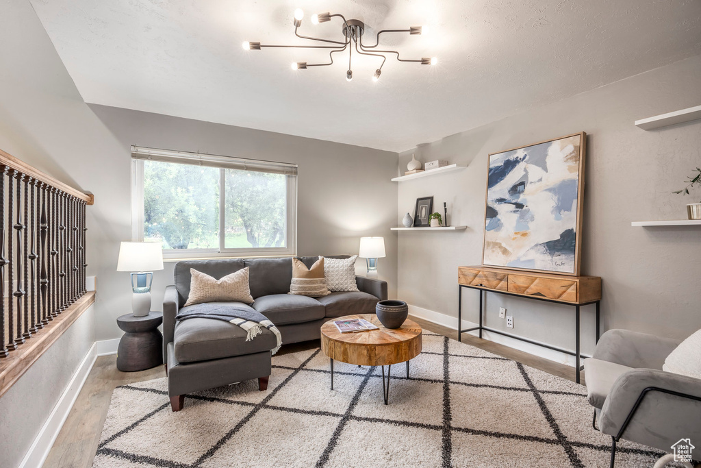 Living room with wood finished floors, baseboards, and a chandelier