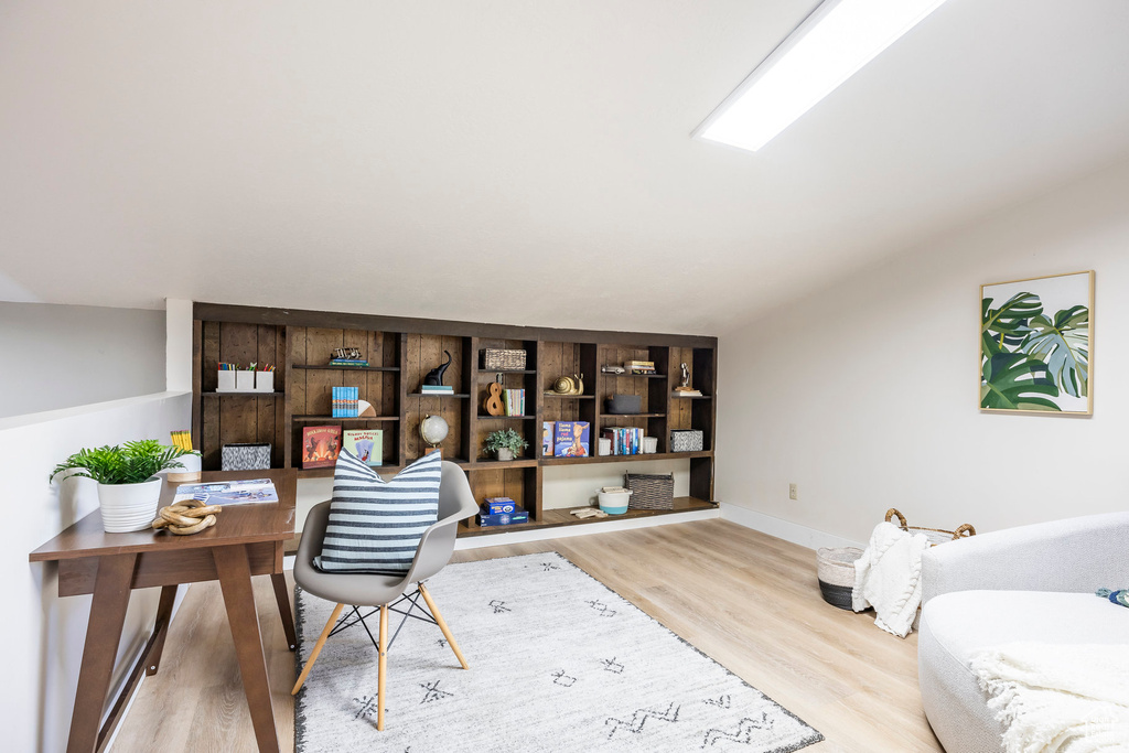 Office area featuring wood finished floors, lofted ceiling, and baseboards
