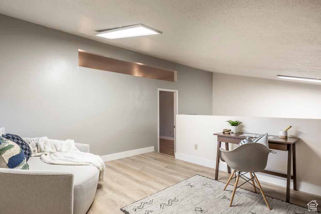 Sitting room featuring a textured ceiling, wood finished floors, baseboards, and an office area