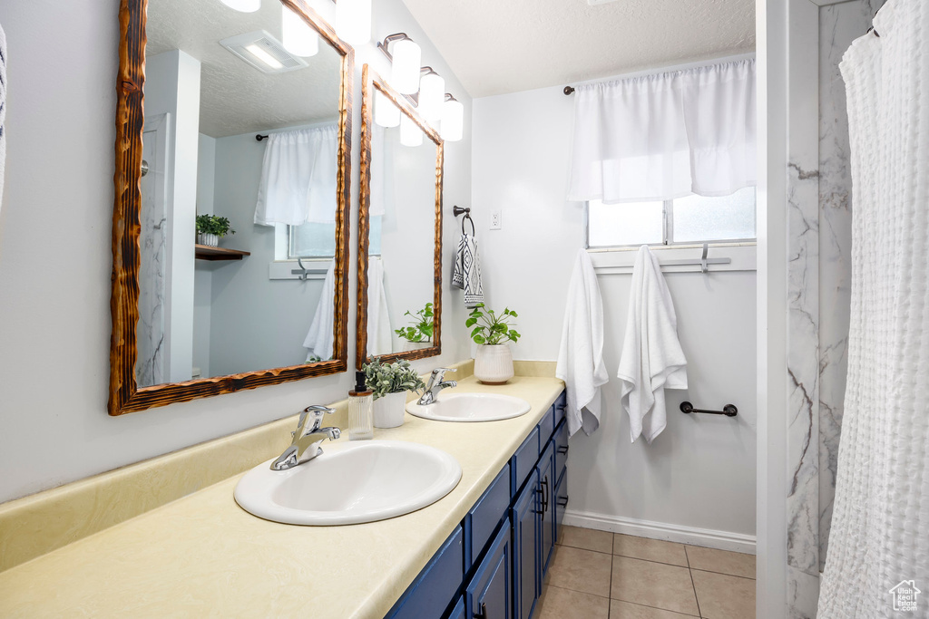 Full bath featuring double vanity and tile patterned flooring