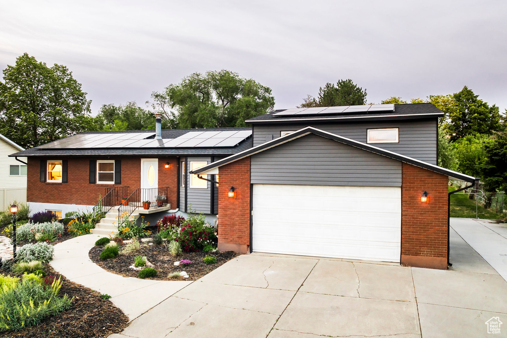 View of front of home with brick siding, solar panels, and a garage