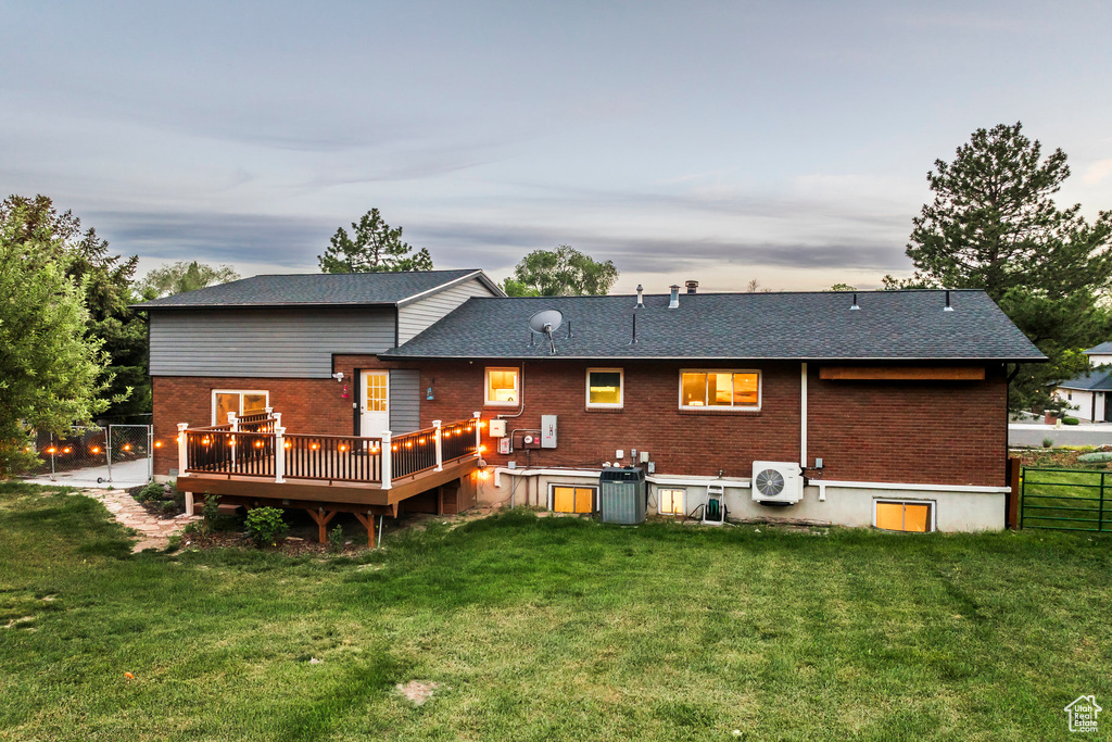 Back of property featuring brick siding, a cooling unit, a deck, cooling unit, and roof with shingles