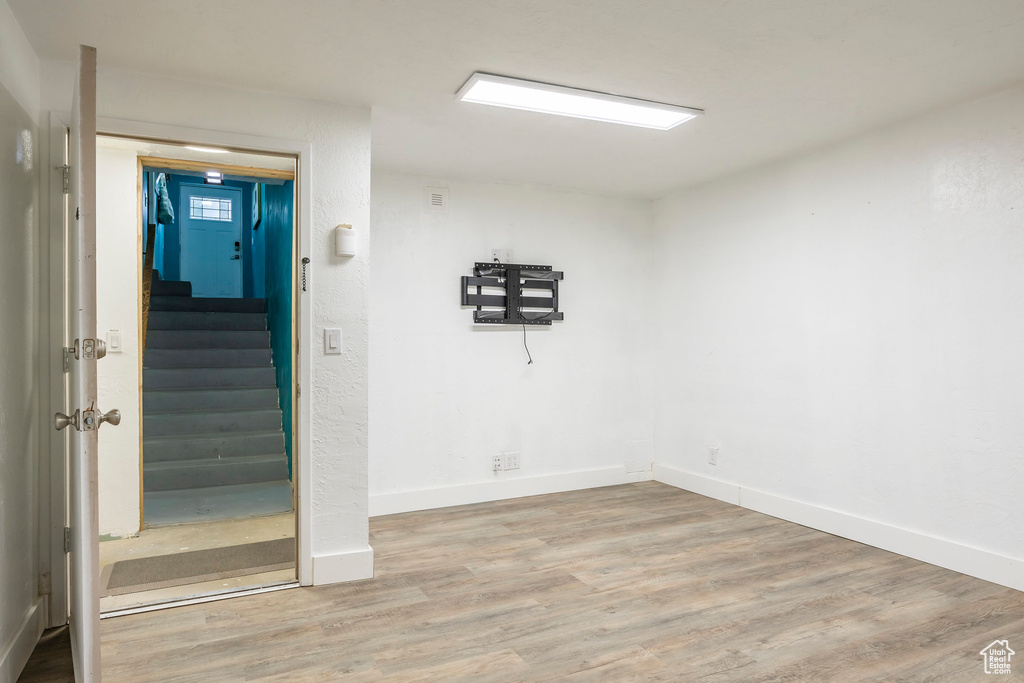 Empty room featuring wood finished floors, stairs, and baseboards