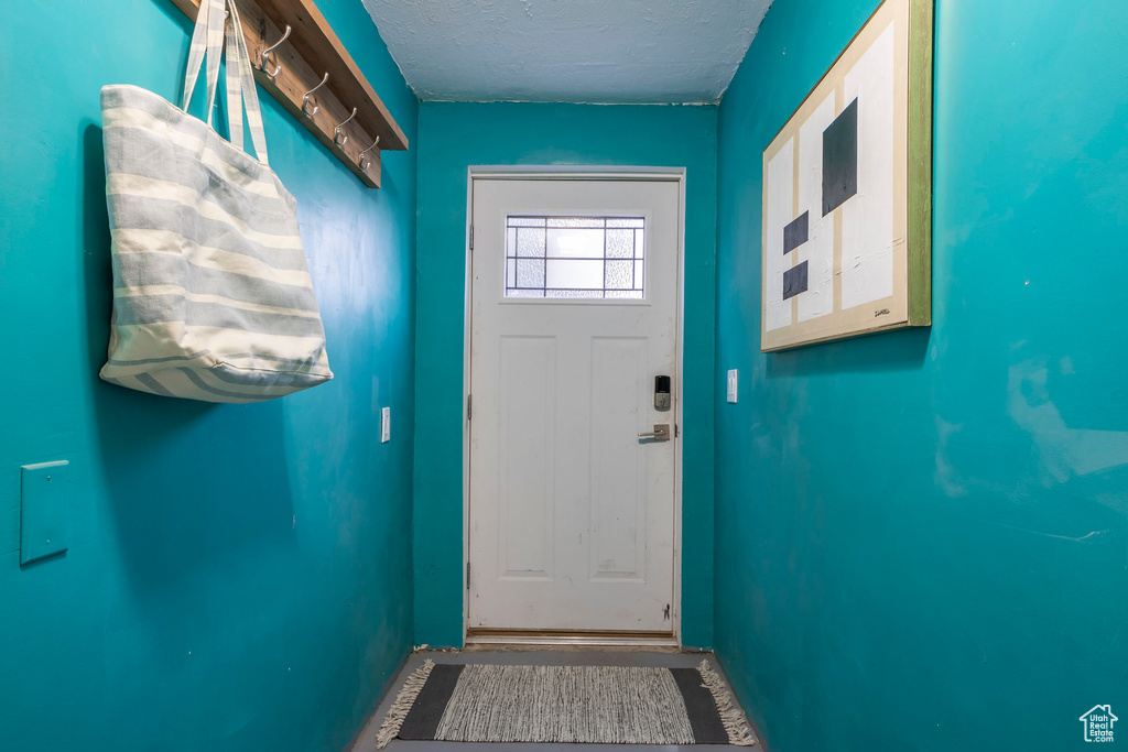 Doorway to outside featuring baseboards and a textured ceiling