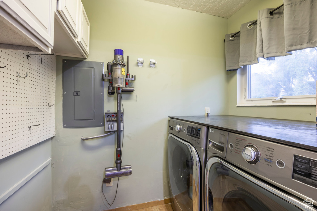 Washroom with cabinet space, washing machine and clothes dryer, electric panel, and a textured ceiling
