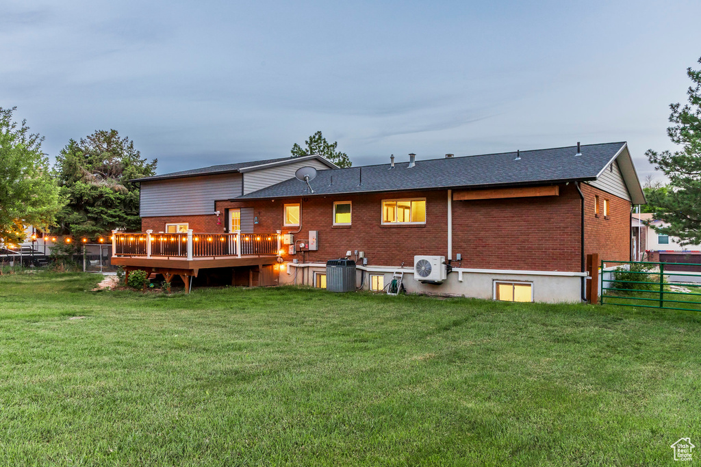 Rear view of house featuring brick siding, a cooling unit, central AC unit, and a wooden deck