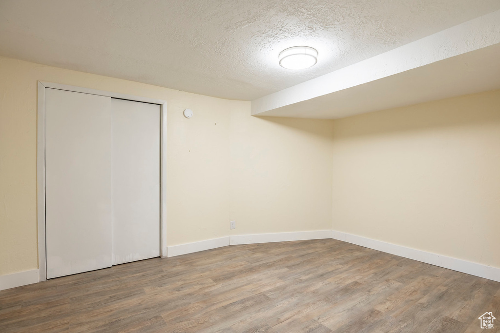 Finished basement with a textured ceiling, wood finished floors, and baseboards
