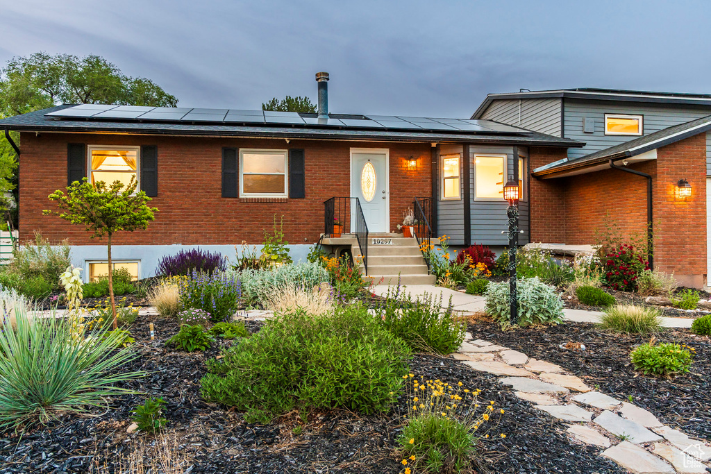 View of front of house with brick siding and solar panels