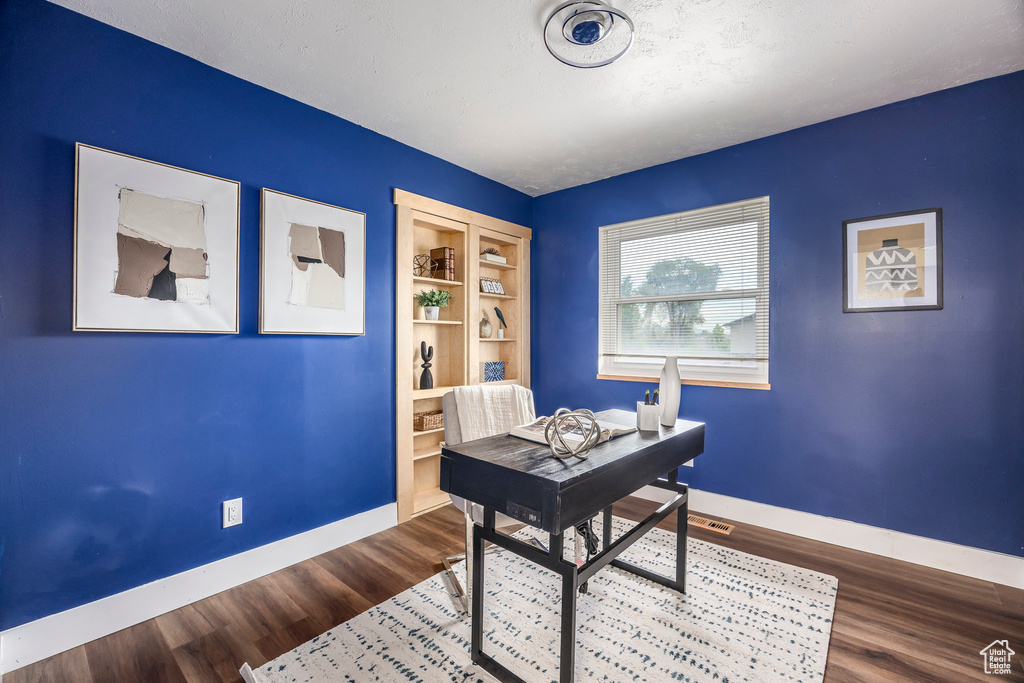Home office with baseboards, built in shelves, and wood finished floors