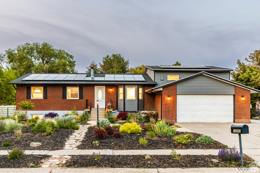 View of front of house with brick siding and roof mounted solar panels