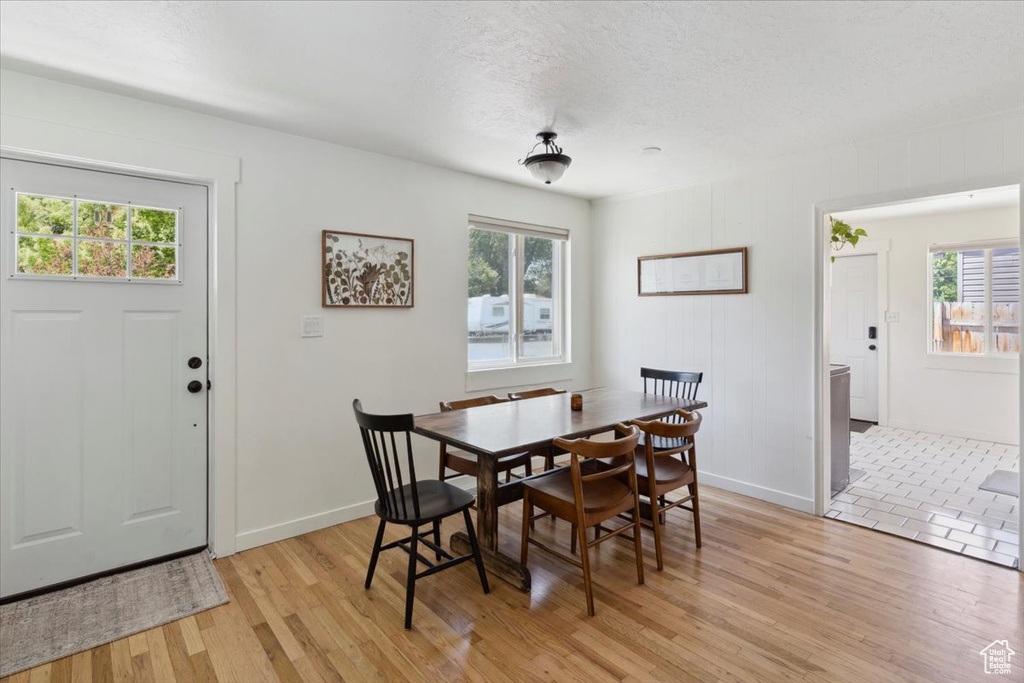 Dining area featuring plenty of natural light, light wood-style flooring, baseboards, and a textured ceiling