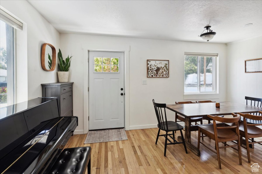 Dining room featuring light wood-style flooring, baseboards, and a textured ceiling