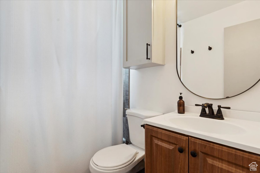 Bathroom featuring toilet, vanity, and a shower with shower curtain