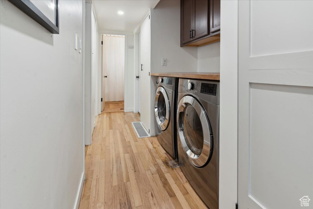 Washroom featuring cabinet space, independent washer and dryer, light wood-style floors, baseboards, and recessed lighting
