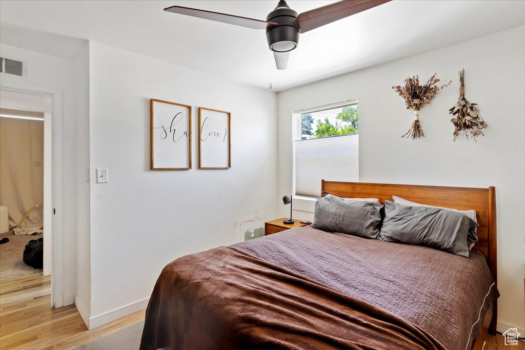 Bedroom with light wood-type flooring, baseboards, and a ceiling fan