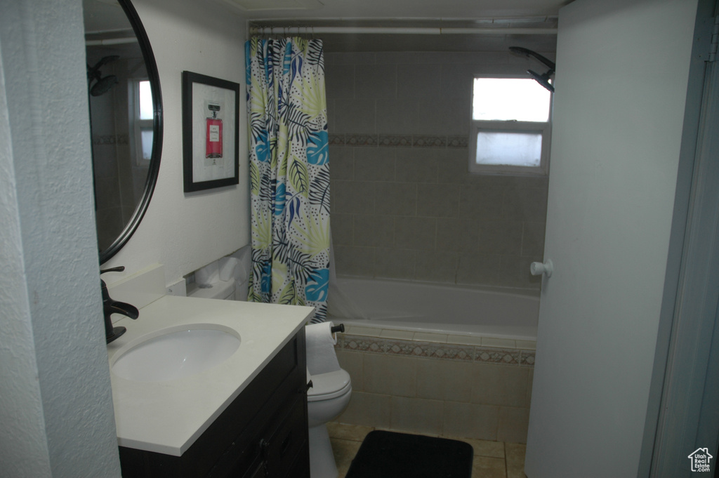 Bathroom featuring tiled shower / bath combo, toilet, tile patterned floors, and vanity