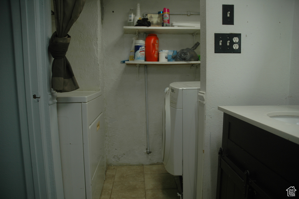 Laundry room with independent washer and dryer and light tile patterned floors