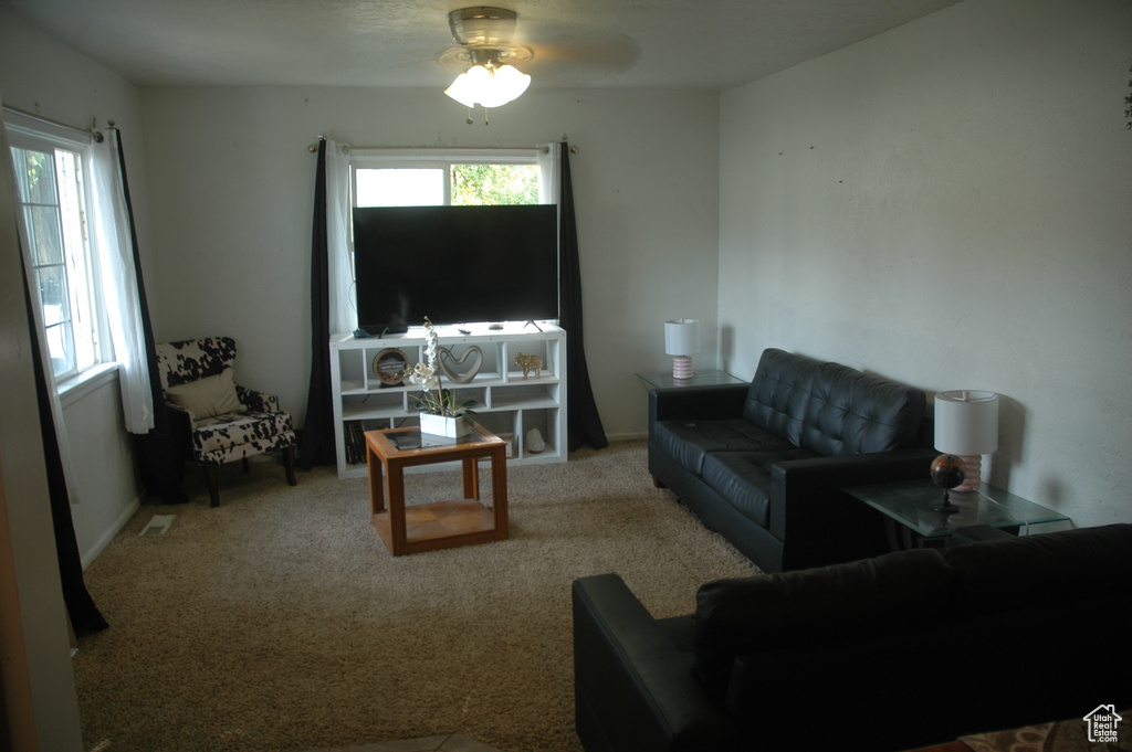 Living area with plenty of natural light, a ceiling fan, and carpet flooring