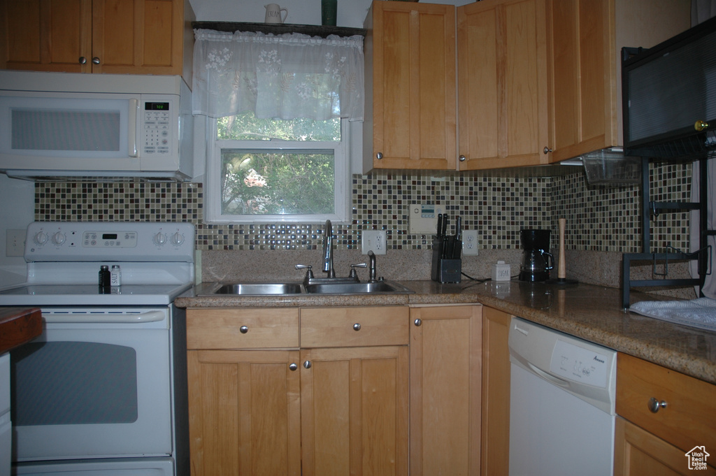 Kitchen featuring white appliances, a sink, and backsplash