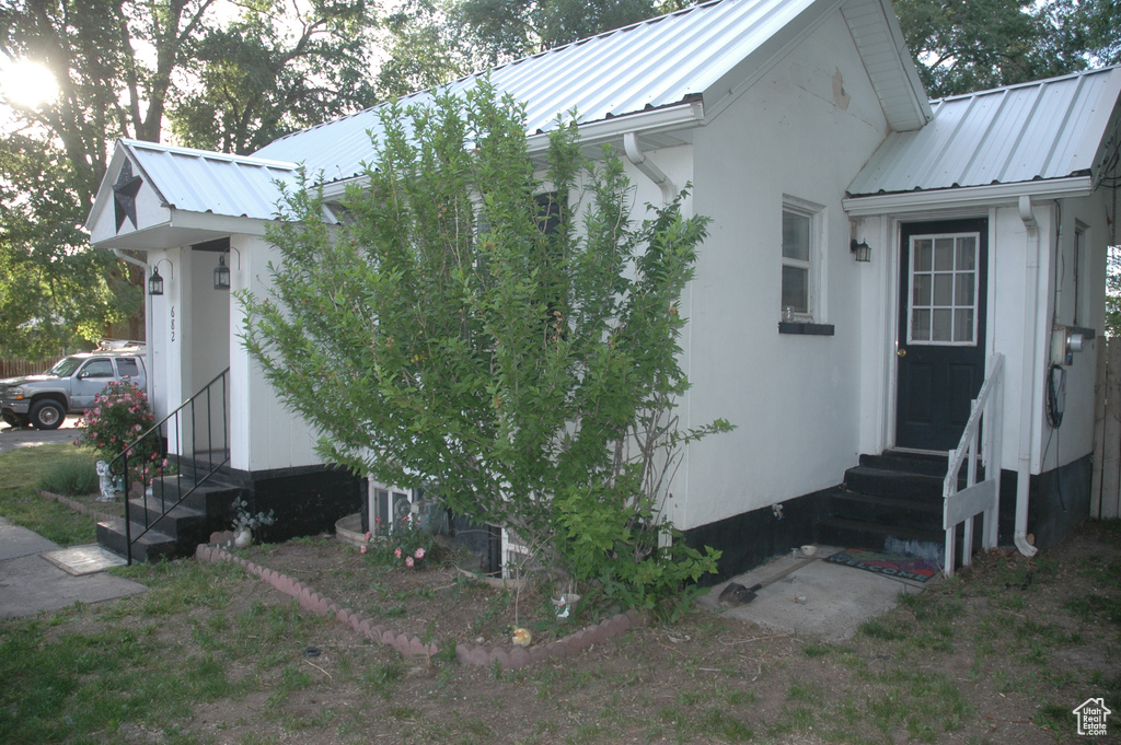 View of side of property with entry steps and metal roof