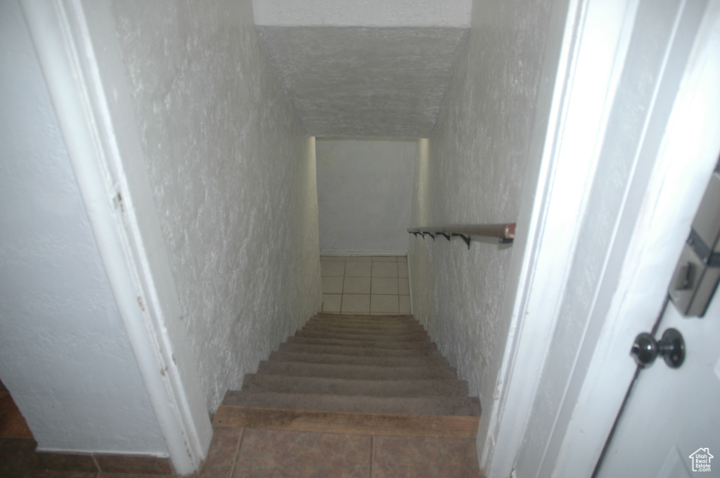 Staircase with tile patterned flooring and a textured wall