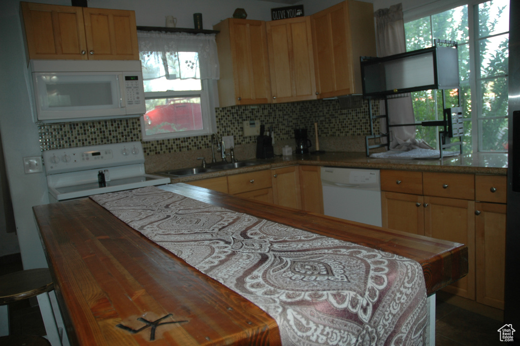 Kitchen with white appliances, a sink, plenty of natural light, and backsplash