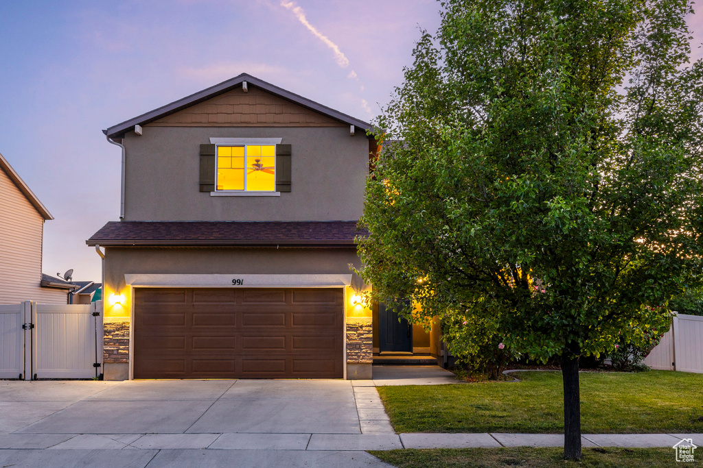 View of front facade featuring stucco siding, driveway, a garage, and stone siding