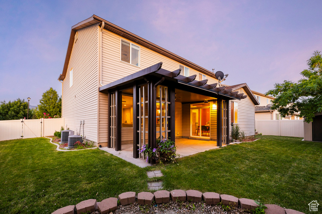 Back of house at dusk featuring a patio area, a gate, and central air condition unit