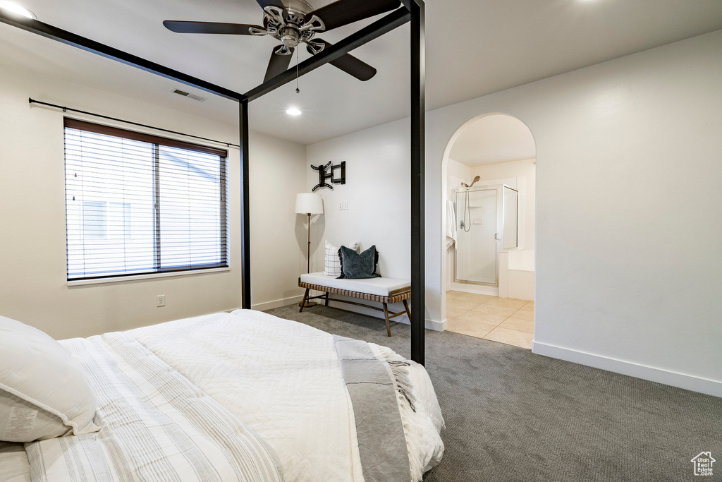 Carpeted bedroom featuring arched walkways, baseboards, connected bathroom, and ceiling fan