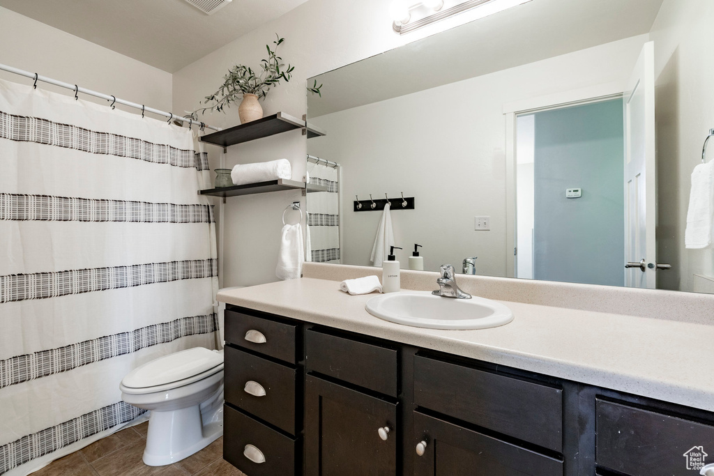 Bathroom with toilet, vanity, tile patterned floors, and curtained shower