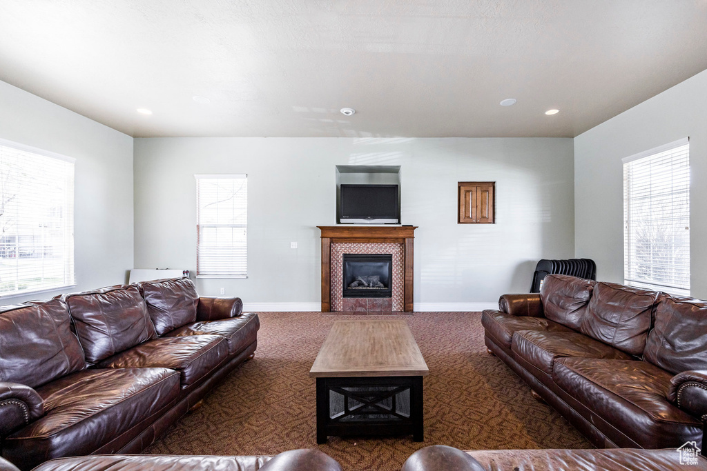 Carpeted living room with a tiled fireplace, baseboards, and recessed lighting