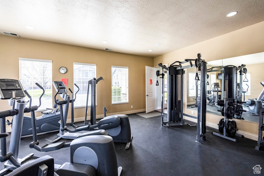 Workout area featuring baseboards, a textured ceiling, and recessed lighting