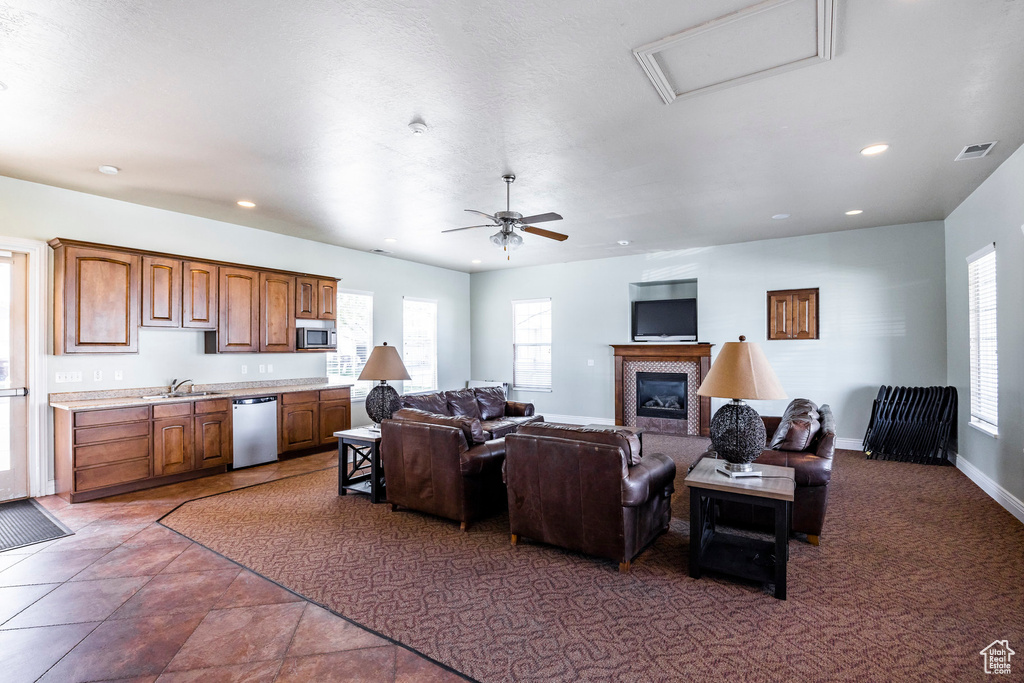 Living room with a glass covered fireplace, recessed lighting, a ceiling fan, attic access, and baseboards