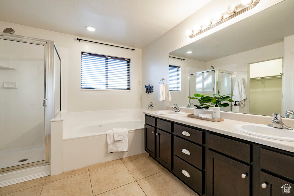 Full bath featuring a shower stall, double vanity, tile patterned flooring, a bath, and a spacious closet