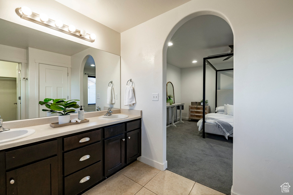 Ensuite bathroom with double vanity, tile patterned floors, and baseboards