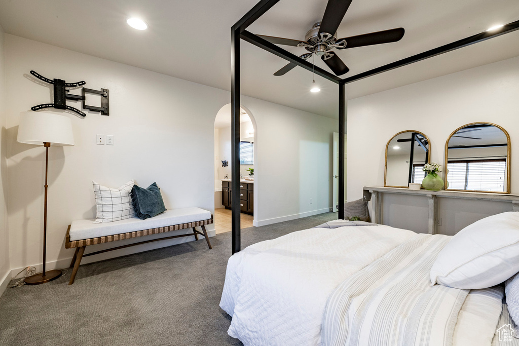 Carpeted bedroom featuring baseboards, recessed lighting, arched walkways, and ensuite bath